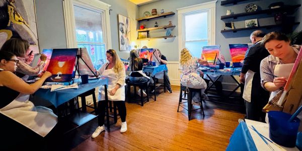 Group painting class with vibrant sunset canvases.