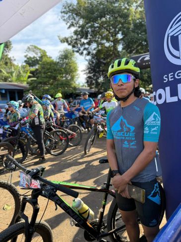 Cyclist in blue gear standing with his bike at a race event.