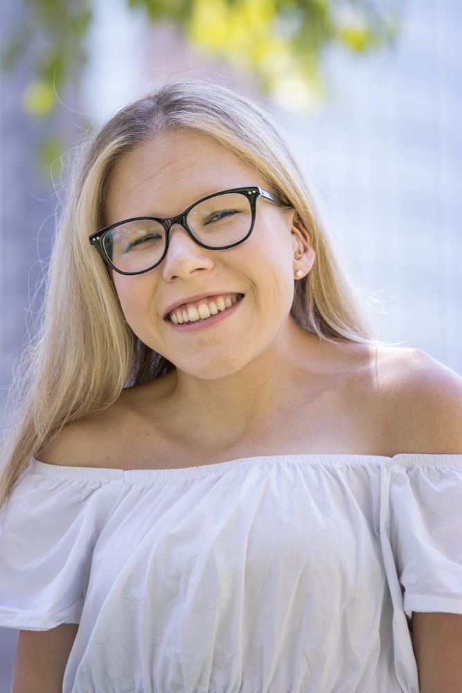 Cassidy Huff is a white woman with long blonde, glasses and an in-ear hearing aid.