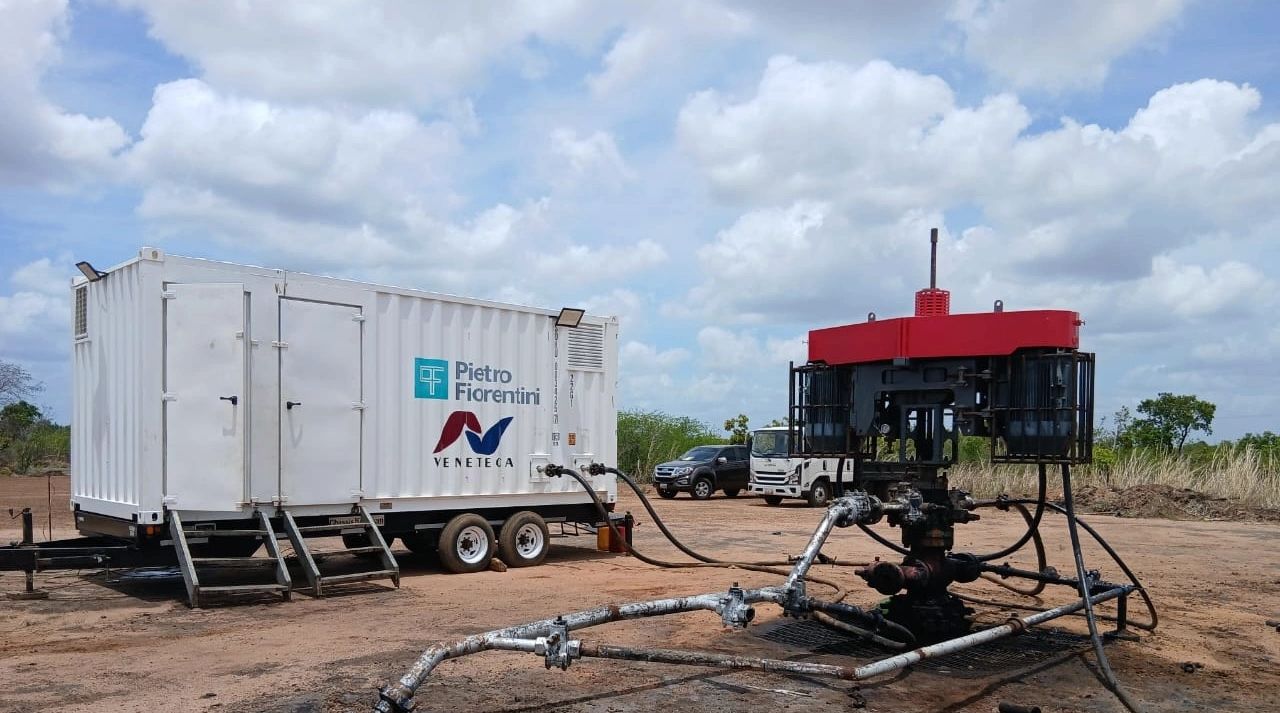 Industrial equipment setup with tank and pipes on a dirt field.