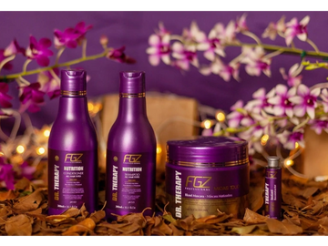 Purple hair care products surrounded by dried leaves and orchids.