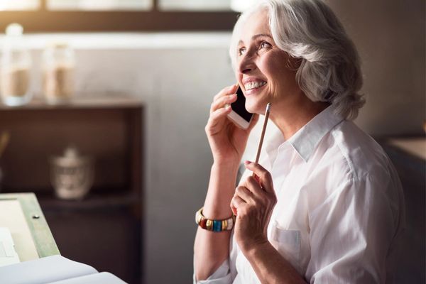 an elderly woman smiling while talking on the phone