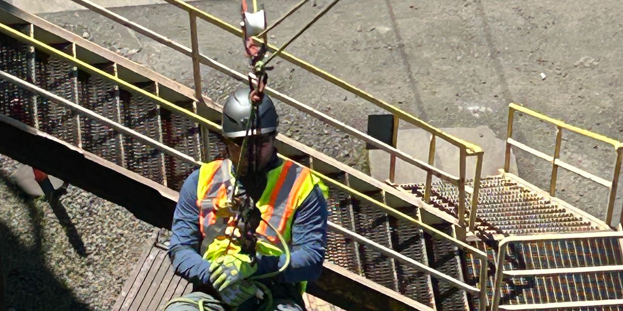 Construction worker securing safety harness on site.
