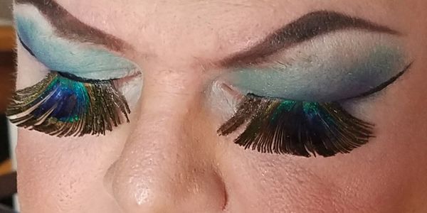 Closeup of a man's eyebrows and eyes covered in makeup. Peacock themed. Classy yet very slutty