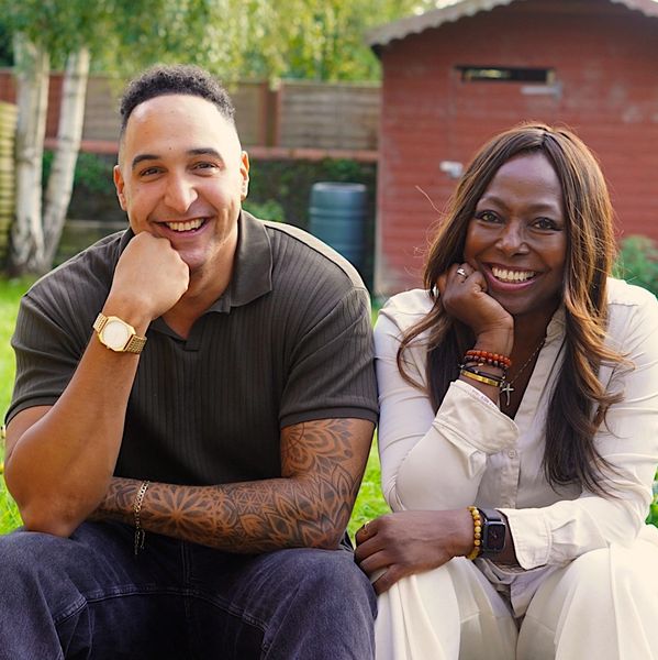 Two people sitting outdoors, smiling warmly at the camera.