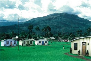 Small houses in front of green mountain