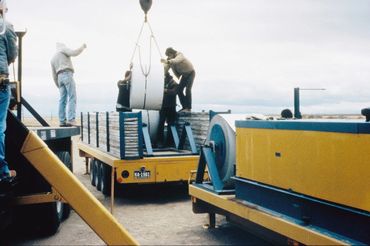 Workers loading metal coil onto machinery