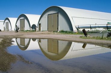 Arched metal buildings reflected in water