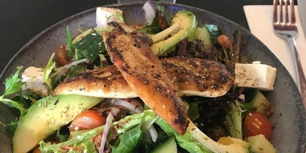 Grilled chicken salad with avocado and mixed greens.