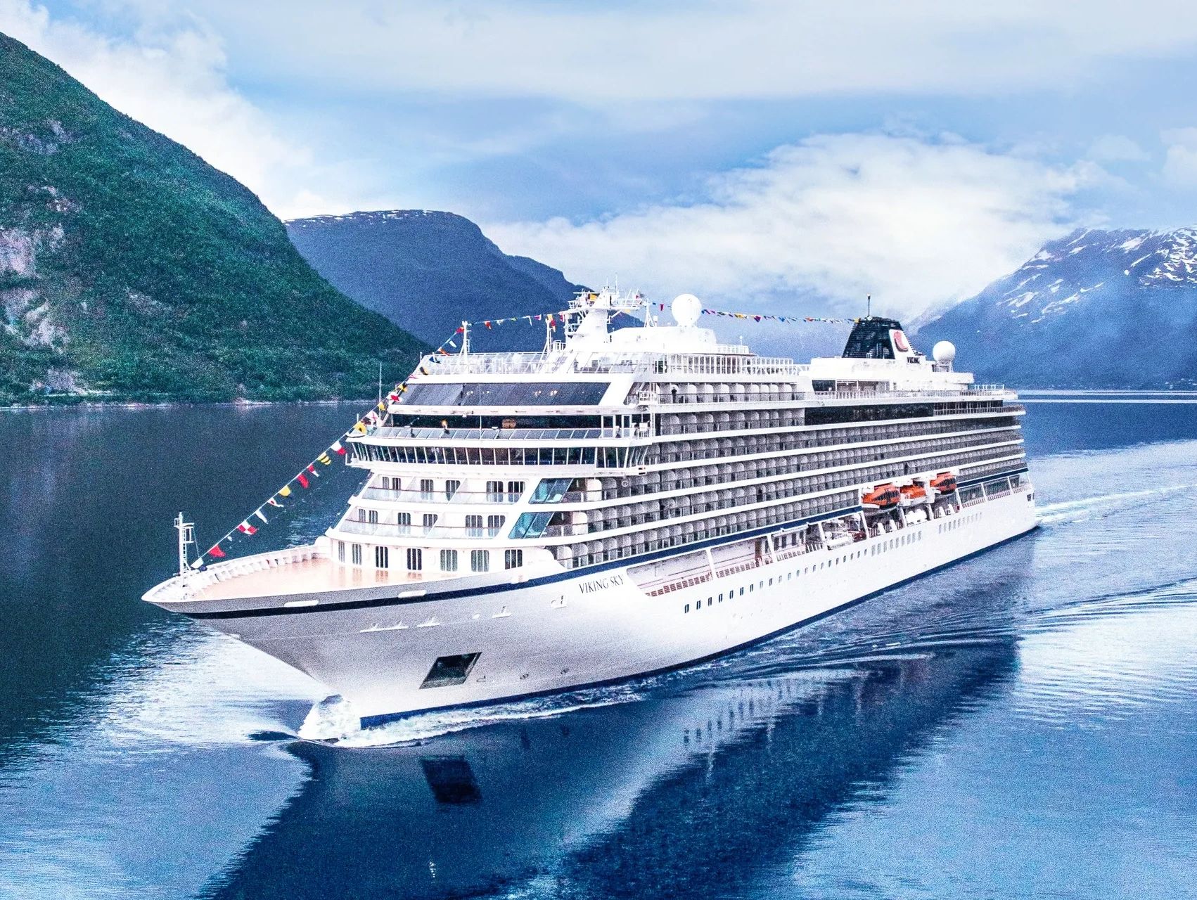 Large cruise ship named Viking Sky sailing in a fjord.