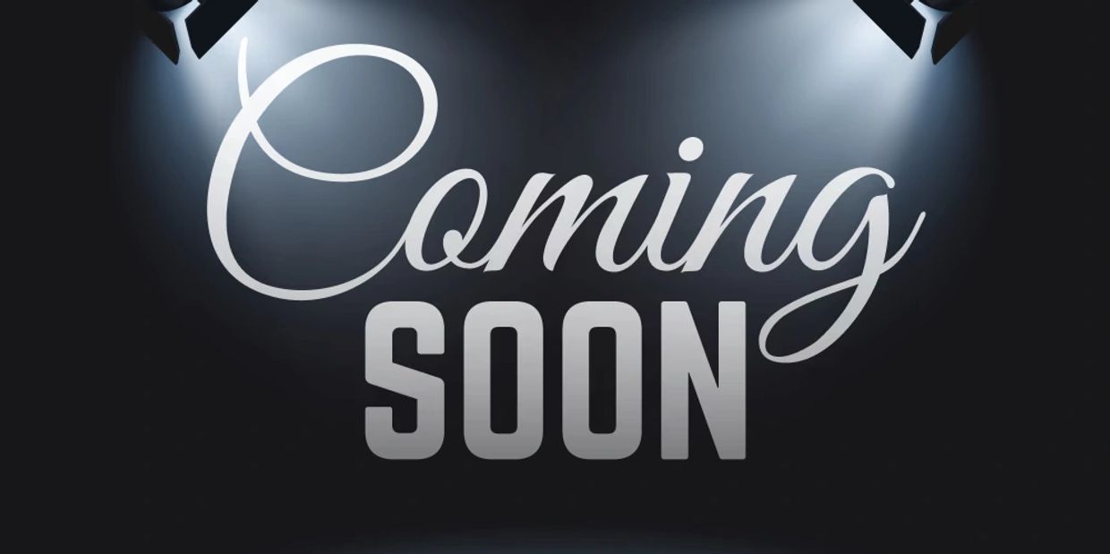Stylish 'Coming Soon' text illuminated by spotlights on a dark background.