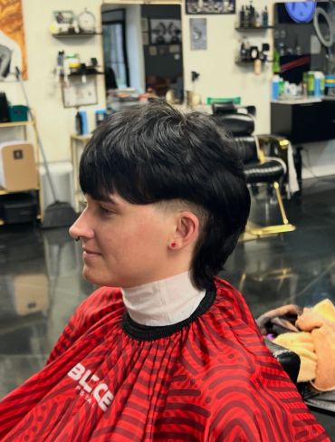 Person with short black haircut in a salon.