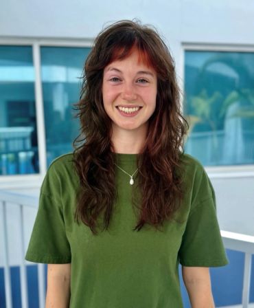 A smiling woman with brown hair in a green shirt.