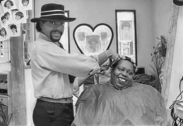 Barber styling a woman's hair in a salon.
