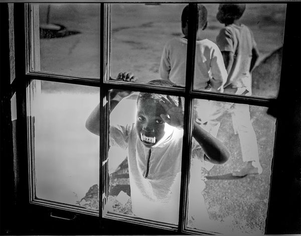 Child looking through a window with toy teeth