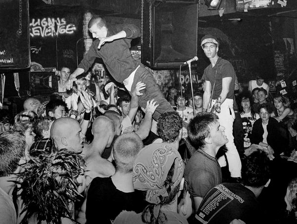 Crowd surfing at a punk rock concert in an underground venue.