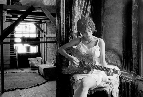 Woman playing guitar in a rustic room.