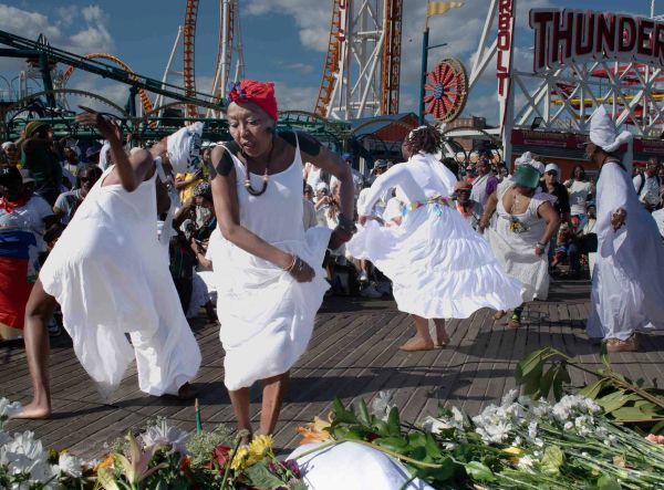Women in white dresses dancing at an outdoor festival.