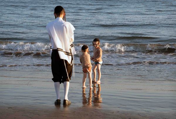 Man and two children playing at the beach.