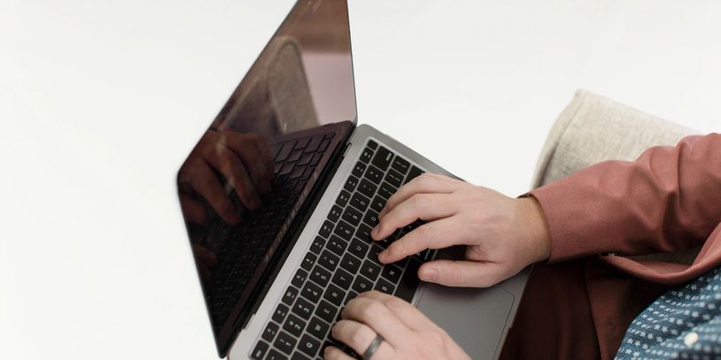 Person typing on a laptop with a reflective screen.