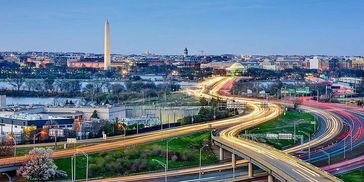 Washington Monument with vibrant city lights and highways at dusk.