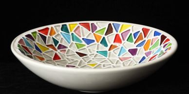 White bowl with colorful mosaic pattern inside on black background.