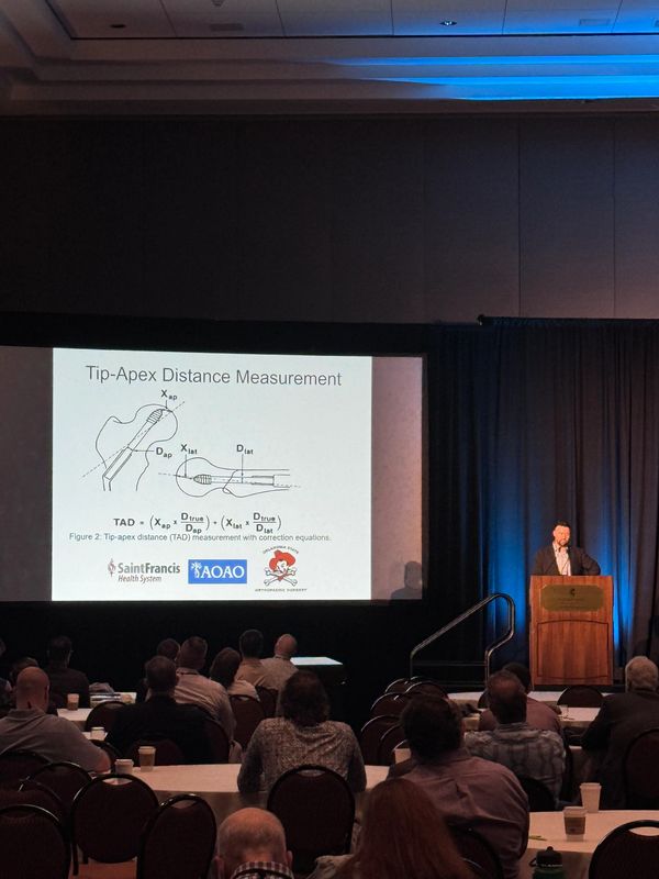 Speaker presenting Tip-Apex Distance Measurement to an attentive audience.
