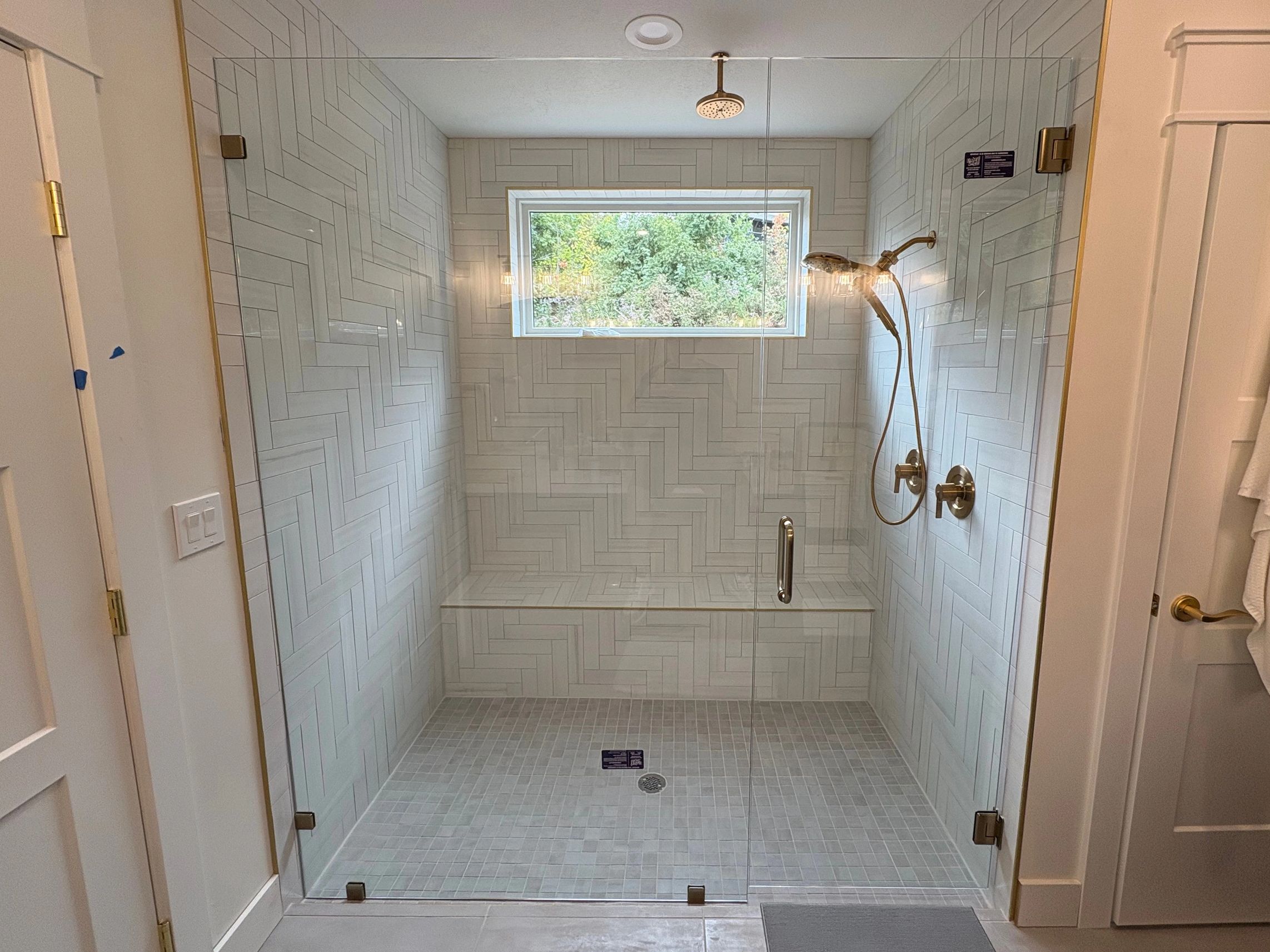 Elegant light colored bathroom with various tile styles and sizes on walls, floor, and shower with a