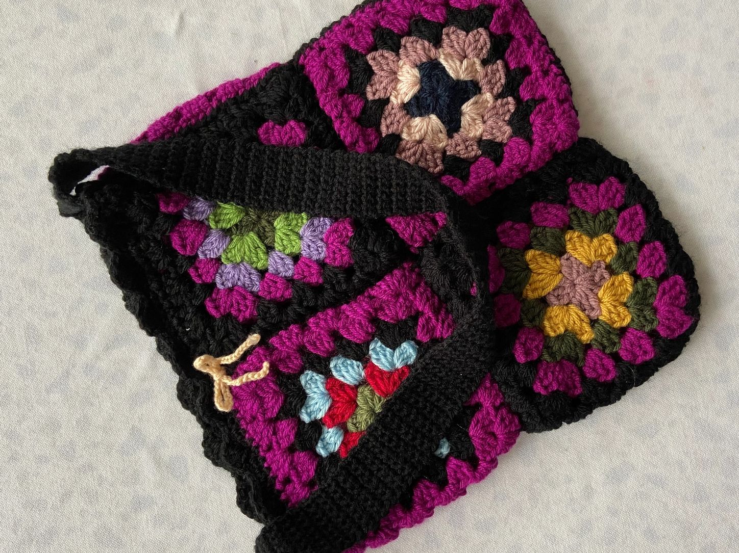 Colorful crocheted granny squares with black borders arranged together.