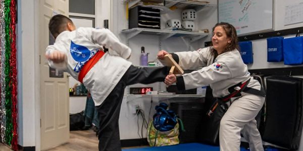 Karate training with a child breaking a wooden board.