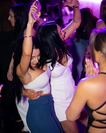 Two women dancing closely together at a lively party with vibrant lighting.