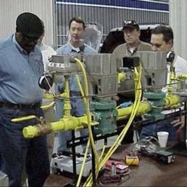 Men experiencing hands-on training simulator learning about fuel trains and controls.