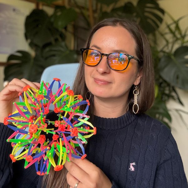 Woman holding a colorful geometric toy.