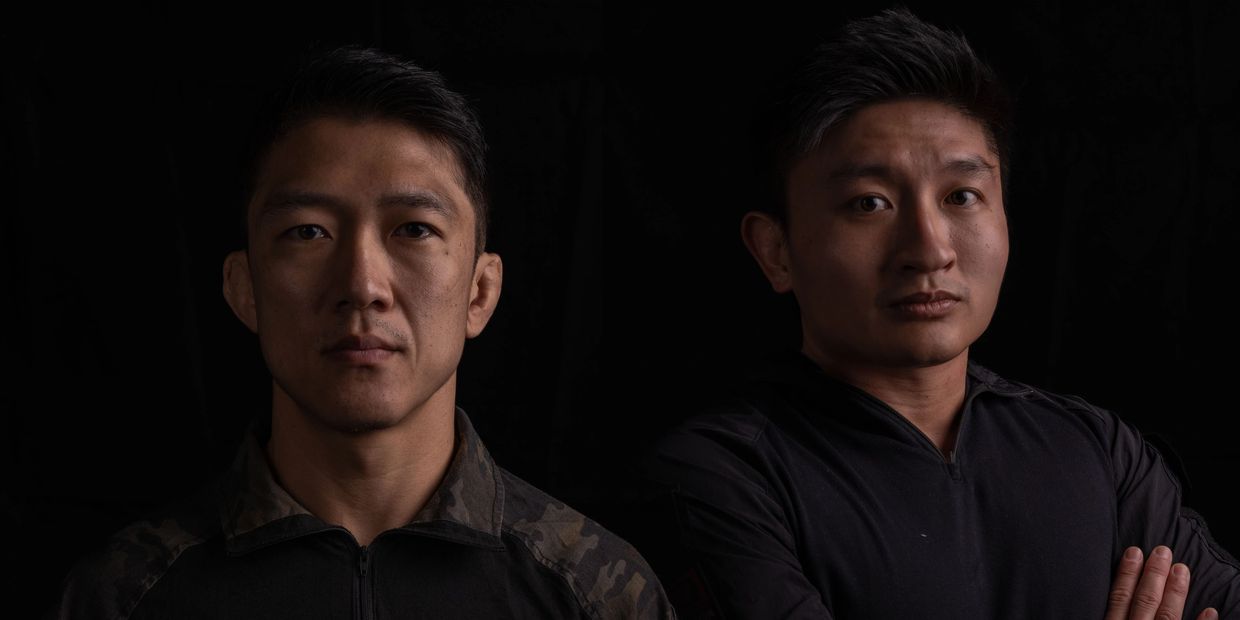 Two serious men posing against a black background.