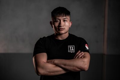 Man with arms crossed wearing a black T-shirt.