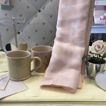Two mugs, a pink cloth, and a flower on a table.