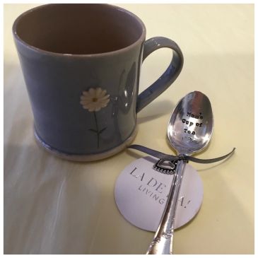 Gray mug with flower and engraved spoon.