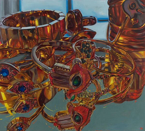 Close-up of shiny gold and jewel-encrusted rings on a reflective surface.