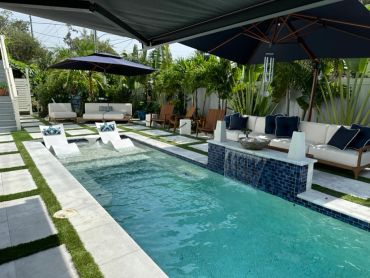 Modern backyard pool with lounge chairs and umbrellas.