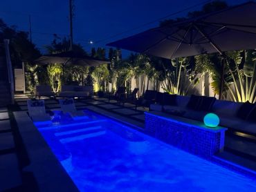 Night view of a lit swimming pool with seating.