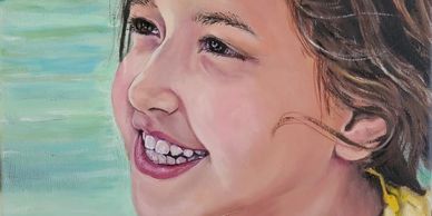 Little girl wearing yellow top, hairing blowing, in front of river, smiling up to the left