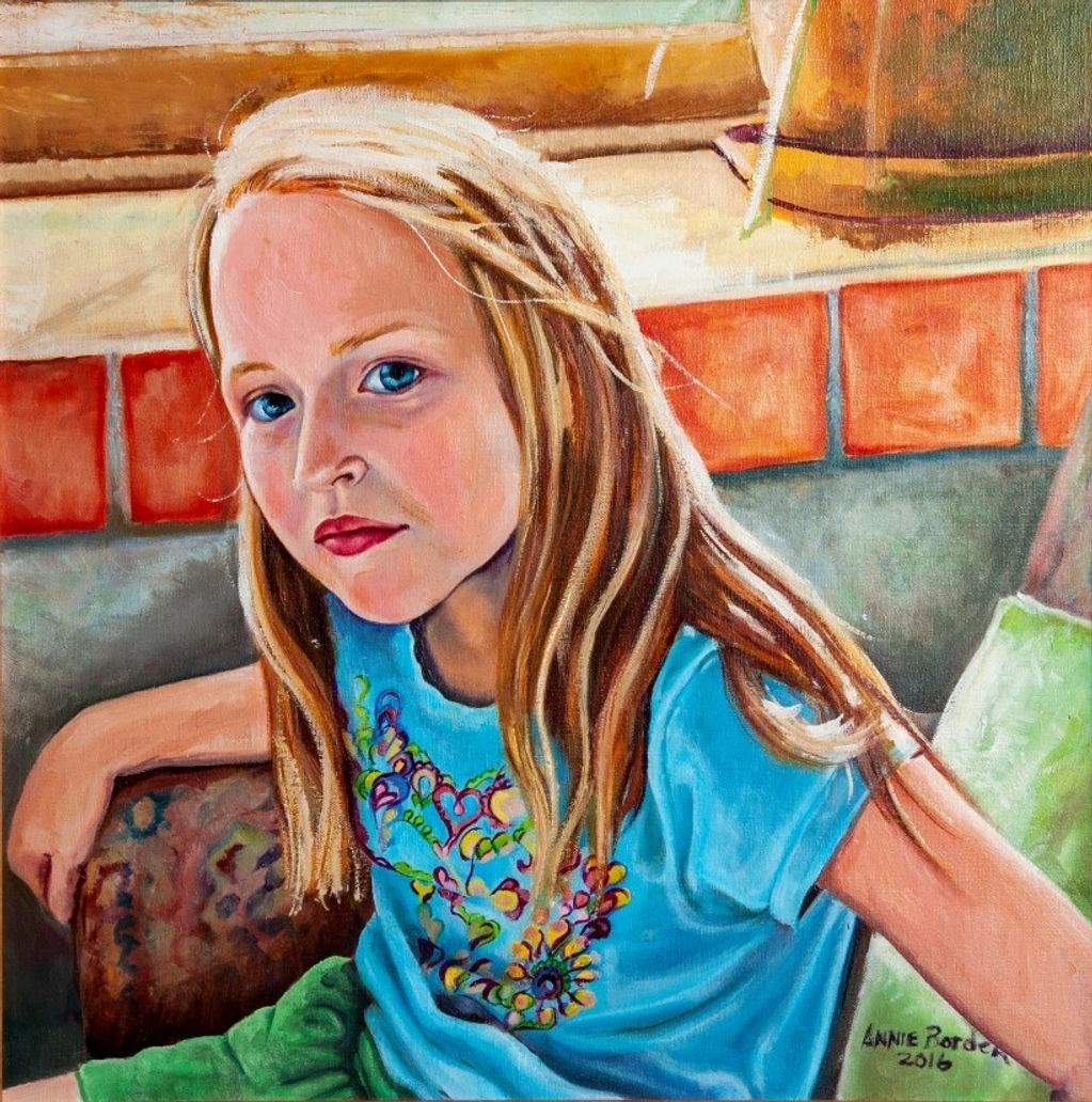 Portrait of young girl looking up at viewer, sitting in paisley chair next to window