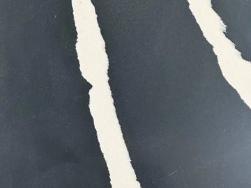 Black paper with white torn strips creating an abstract design.