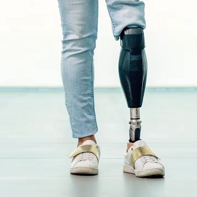 Person wearing a black prosthetic leg with light blue jeans and white sneakers.