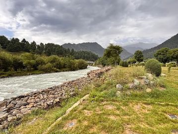 A scenic river flowing through a green landscape under a cloudy sky.