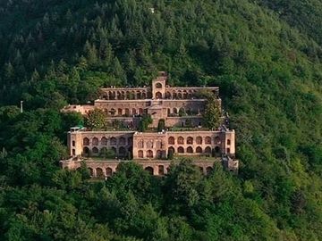 A terraced building nestled in lush green mountains.