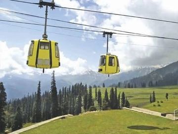 Yellow cable cars moving over a green mountainous landscape.
