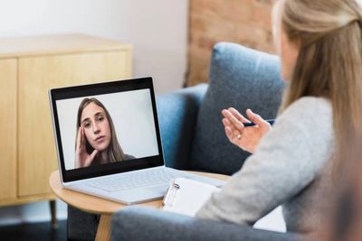 Two women engaged in a video call, one taking notes.