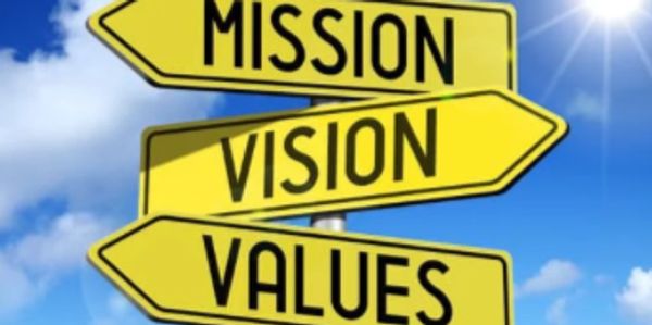 Yellow directional signs labeled Mission, Vision, and Values against a blue sky.