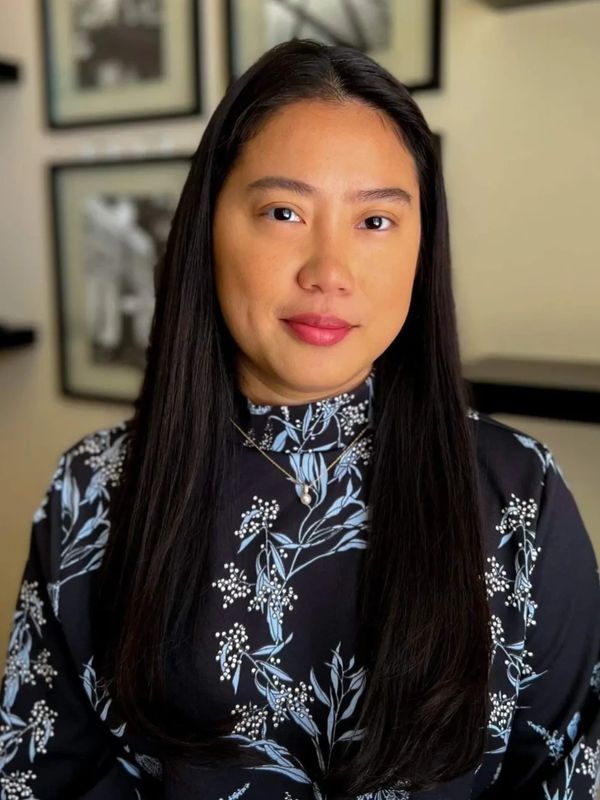 Portrait of a woman with long dark hair wearing a floral patterned top.